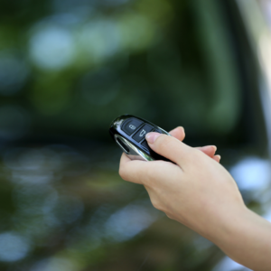 his image shows a woman unlocking a car by pressing on the remote control car alarm systems